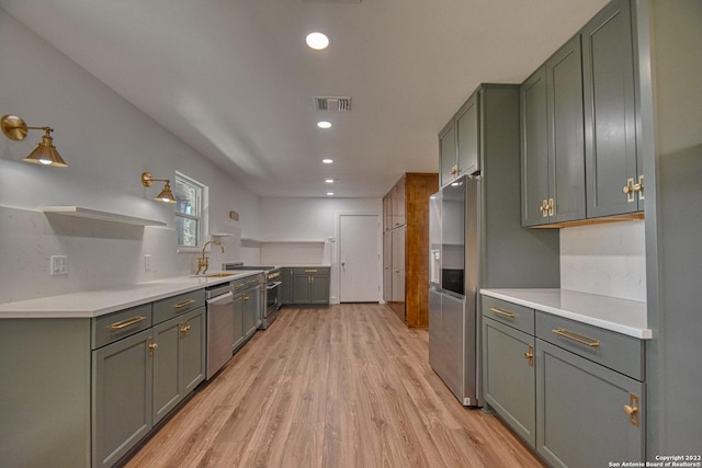 kitchen featuring green cabinets, light wood-type flooring, and appliances with stainless steel finishes