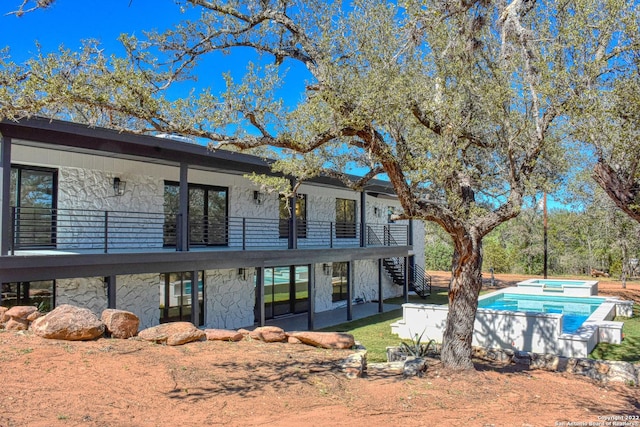 back of house featuring a swimming pool with hot tub