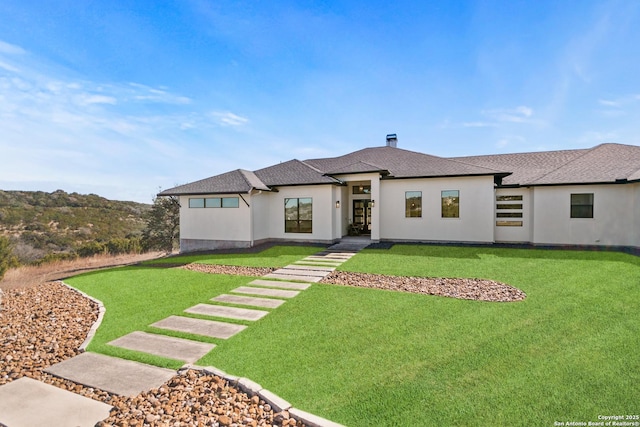 prairie-style home featuring a shingled roof, a front lawn, and stucco siding