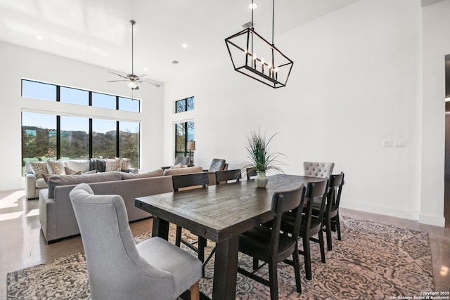 dining room with recessed lighting, a high ceiling, finished concrete floors, baseboards, and ceiling fan with notable chandelier