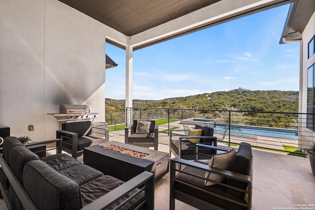 view of patio with an outdoor living space with a fire pit, a view of trees, and grilling area