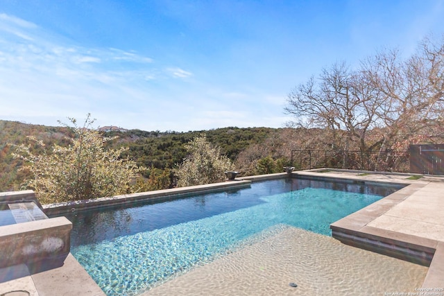 outdoor pool featuring fence and a hot tub