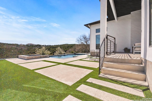 pool with an in ground hot tub and a patio area