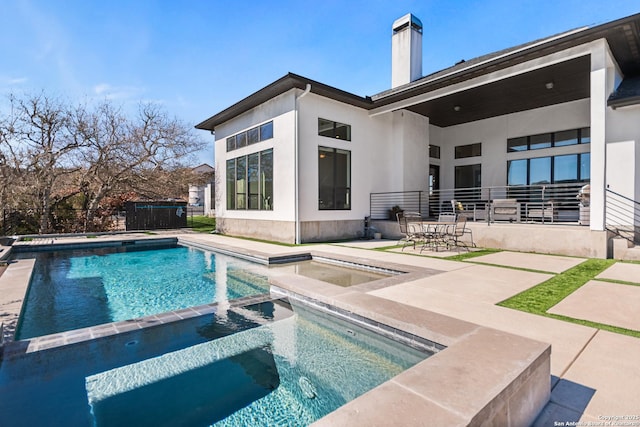 view of pool with a patio area, fence, and a pool with connected hot tub