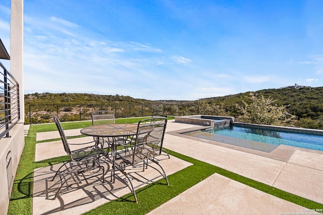 view of pool featuring a pool with connected hot tub, fence, and a patio