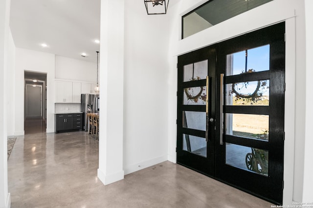 entryway featuring a healthy amount of sunlight, finished concrete floors, baseboards, and a high ceiling