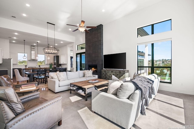 living area featuring finished concrete flooring, baseboards, a towering ceiling, and recessed lighting