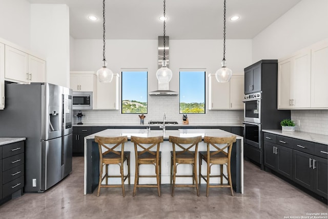 kitchen with an island with sink, appliances with stainless steel finishes, dark cabinets, and white cabinets