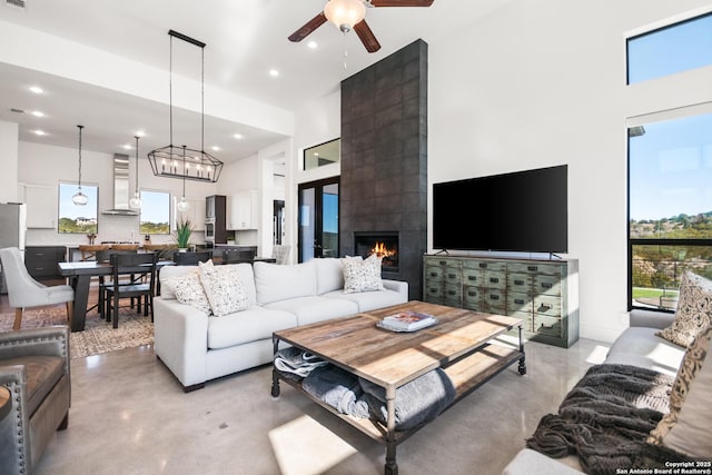 living room featuring concrete flooring, a high ceiling, a ceiling fan, and recessed lighting