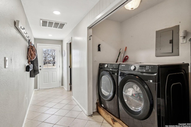 clothes washing area with electric panel, washer and clothes dryer, and light tile patterned floors