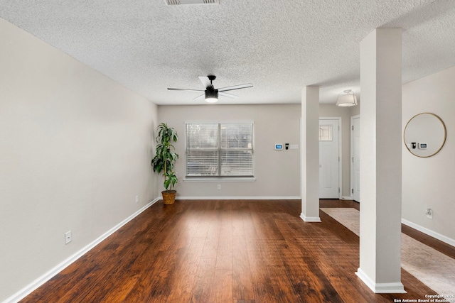 unfurnished living room with ornate columns, dark hardwood / wood-style floors, a textured ceiling, and ceiling fan