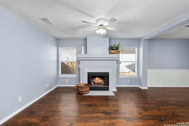 unfurnished living room with dark hardwood / wood-style flooring, a textured ceiling, a high end fireplace, and ceiling fan