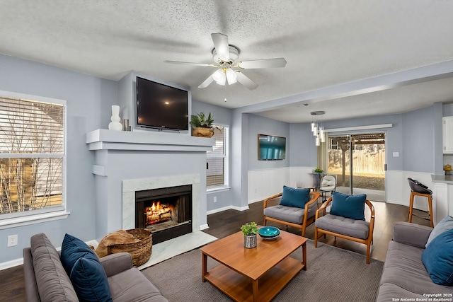 living room featuring ceiling fan, dark wood-type flooring, a textured ceiling, and a high end fireplace