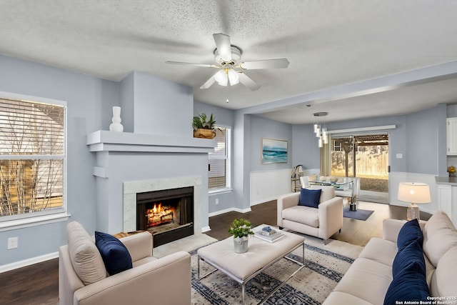 living room featuring a premium fireplace, hardwood / wood-style floors, ceiling fan, and a textured ceiling