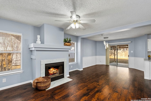 unfurnished living room with dark hardwood / wood-style flooring, a textured ceiling, a high end fireplace, and ceiling fan