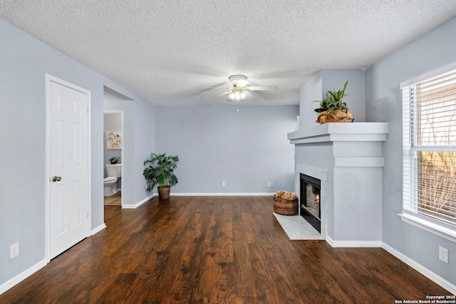 unfurnished living room featuring ceiling fan, built in features, dark hardwood / wood-style floors, and a textured ceiling