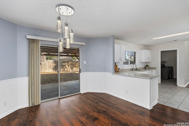 kitchen featuring decorative light fixtures, white cabinetry, sink, kitchen peninsula, and dark wood-type flooring