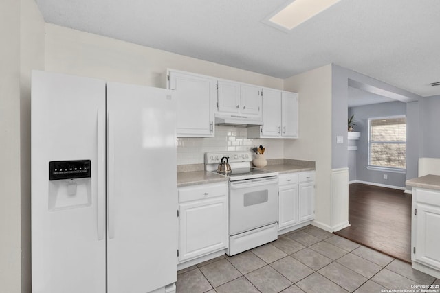 kitchen with white cabinetry, light tile patterned floors, white appliances, and tasteful backsplash