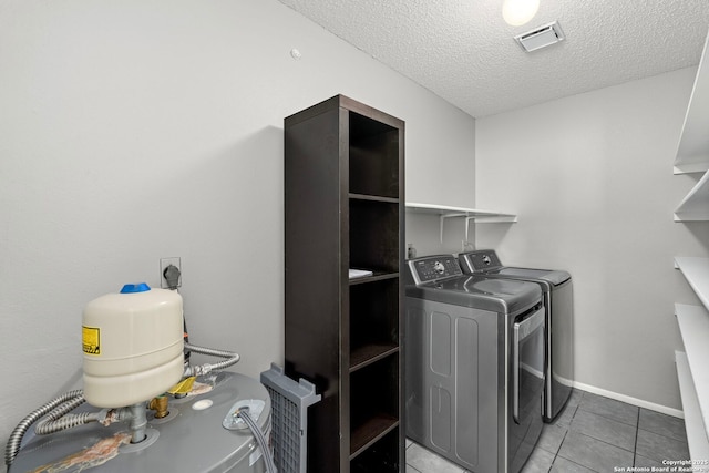 laundry area with washing machine and clothes dryer, tile patterned floors, and a textured ceiling