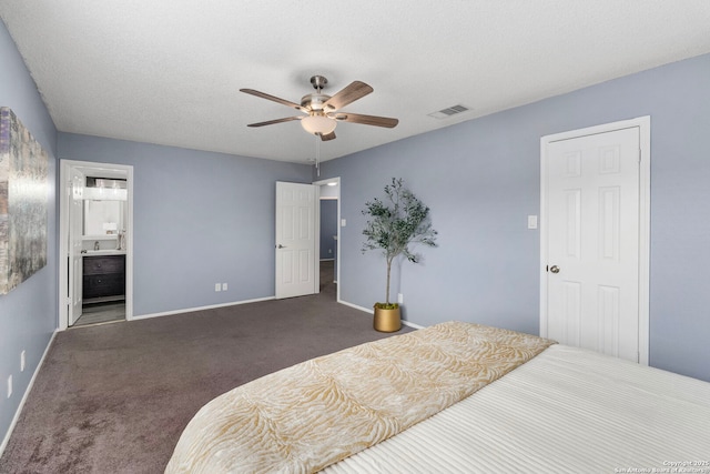 carpeted bedroom featuring ceiling fan, ensuite bath, and a textured ceiling