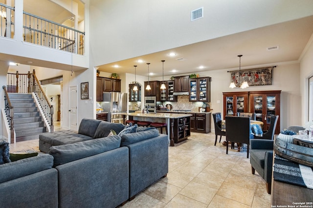 living room with light tile patterned floors, crown molding, and a towering ceiling