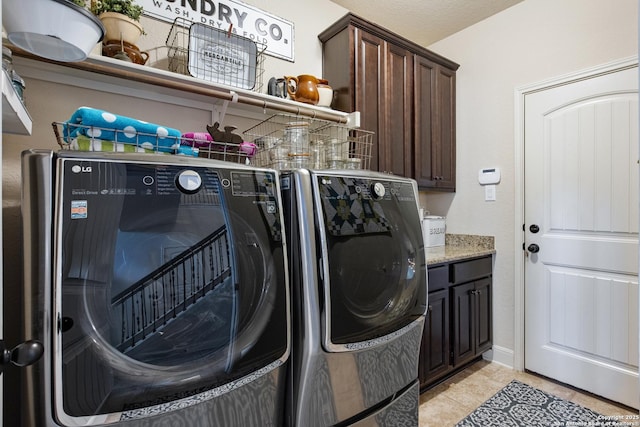 clothes washing area featuring light tile patterned floors, cabinets, and washing machine and clothes dryer