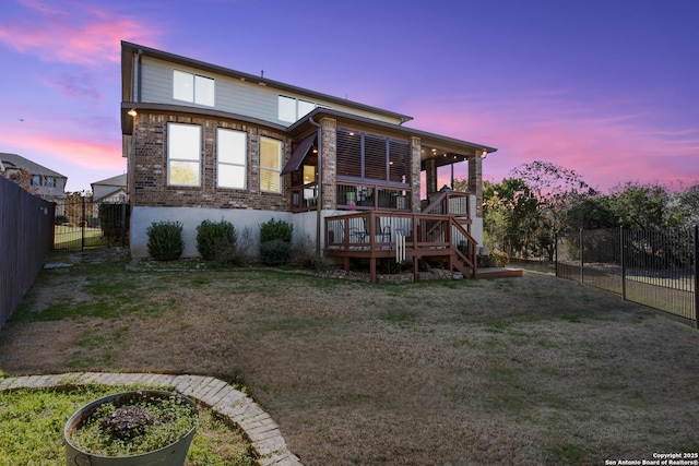 back house at dusk with a yard and a deck