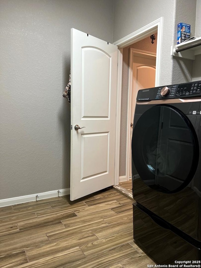 clothes washing area with washer / clothes dryer and wood-type flooring