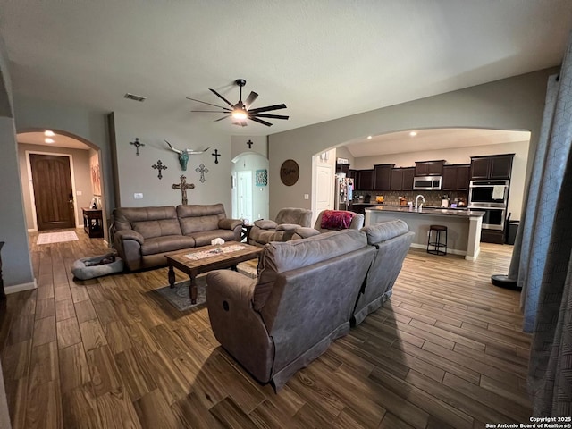 living room with ceiling fan, vaulted ceiling, and dark hardwood / wood-style flooring