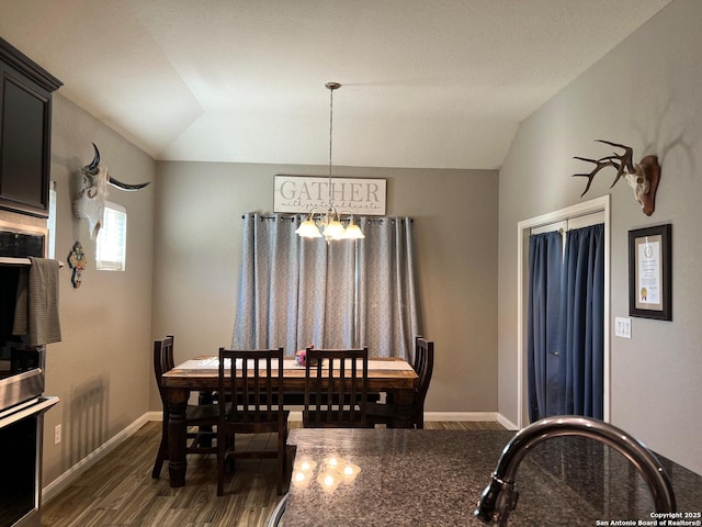 dining room with dark wood-type flooring, lofted ceiling, and a chandelier