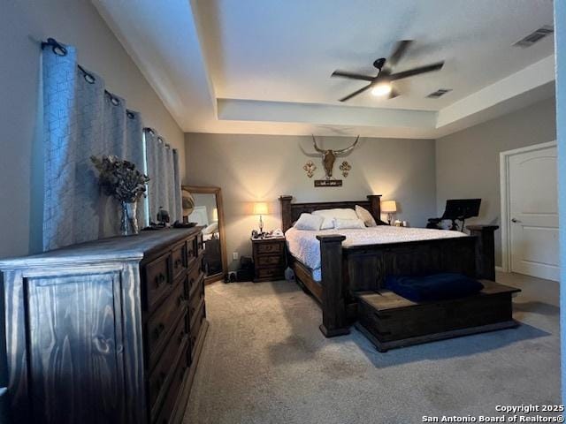 bedroom featuring light colored carpet, a raised ceiling, and ceiling fan