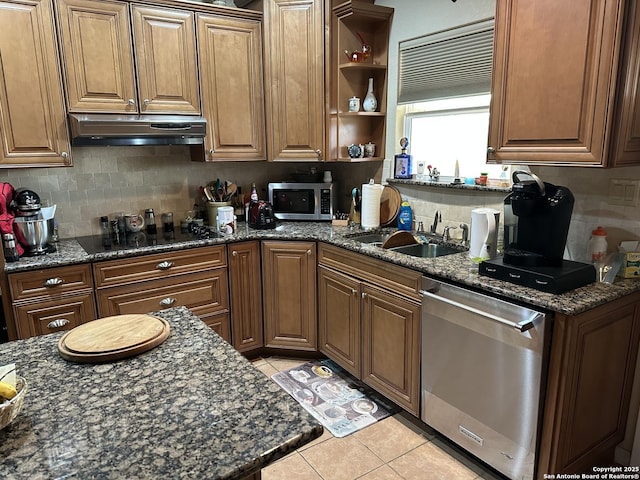 kitchen with sink, stainless steel appliances, dark stone counters, and light tile patterned flooring