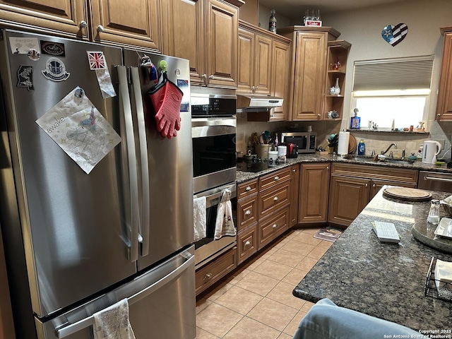 kitchen featuring stainless steel appliances, sink, dark stone counters, and light tile patterned floors