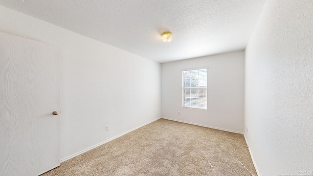 carpeted empty room featuring a textured ceiling