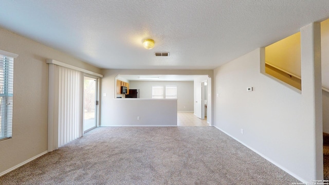 unfurnished living room with light carpet and a textured ceiling