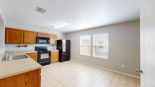 kitchen with sink, a textured ceiling, and black appliances