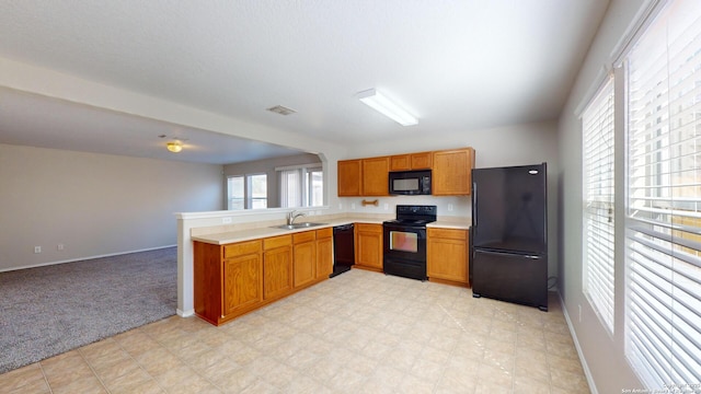 kitchen with light carpet, sink, black appliances, and kitchen peninsula