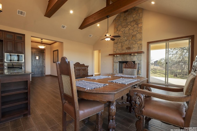 dining area with ceiling fan, a stone fireplace, high vaulted ceiling, and beam ceiling