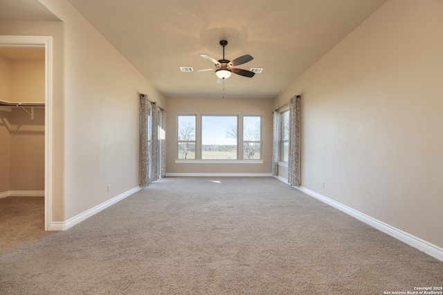 unfurnished bedroom with a spacious closet, a textured ceiling, carpet flooring, a closet, and ceiling fan