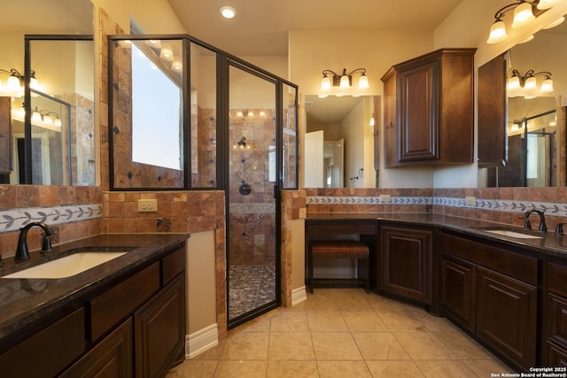 bathroom featuring a stall shower, tile patterned flooring, two vanities, and a sink