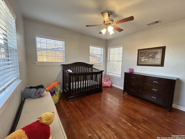 bedroom with multiple windows, dark hardwood / wood-style floors, and ceiling fan