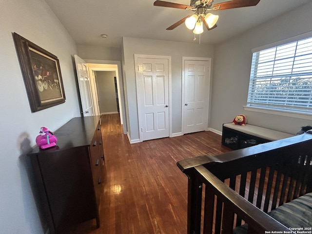 bedroom featuring ceiling fan, dark hardwood / wood-style floors, and multiple closets