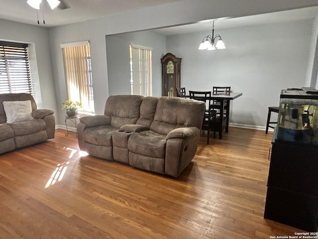 living room with wood-type flooring and ceiling fan with notable chandelier