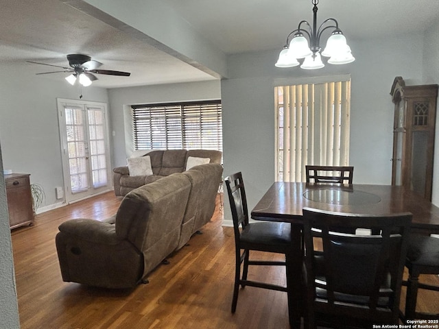 dining room with ceiling fan with notable chandelier and dark hardwood / wood-style floors