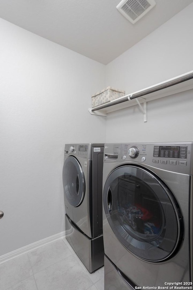 laundry room featuring washer and dryer and light tile patterned flooring