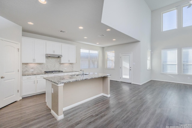 kitchen with white cabinetry, wood-type flooring, sink, an island with sink, and stainless steel gas cooktop