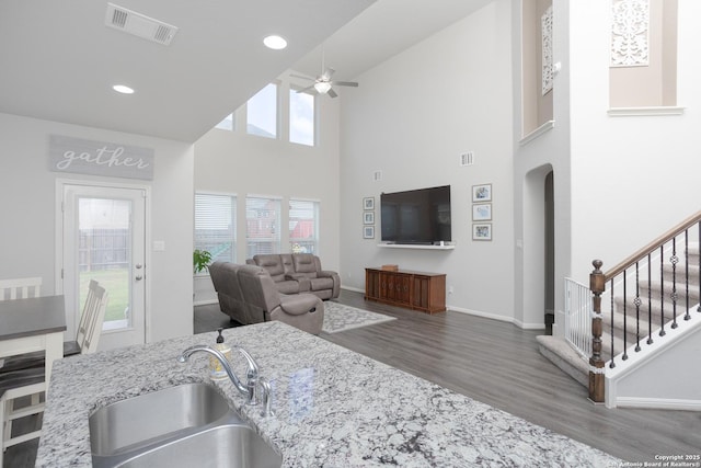 kitchen featuring sink, hardwood / wood-style flooring, a high ceiling, ceiling fan, and light stone counters