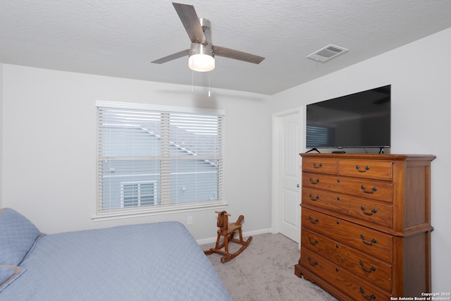 bedroom with ceiling fan, light colored carpet, and a textured ceiling