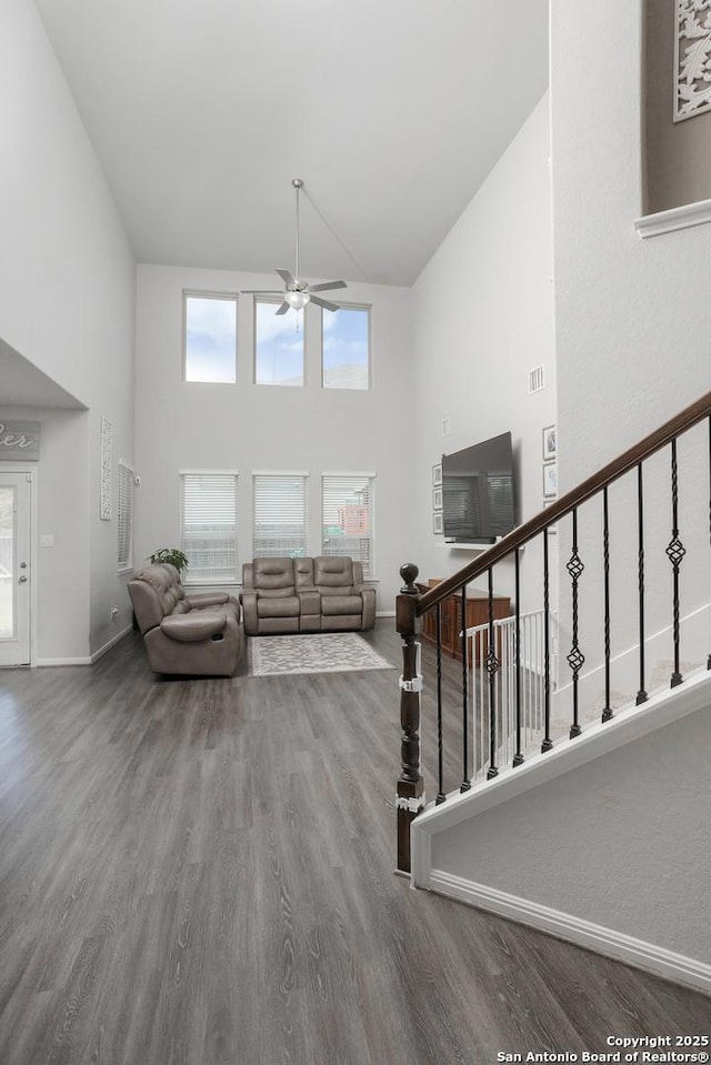 living room with hardwood / wood-style flooring, a healthy amount of sunlight, ceiling fan, and a towering ceiling