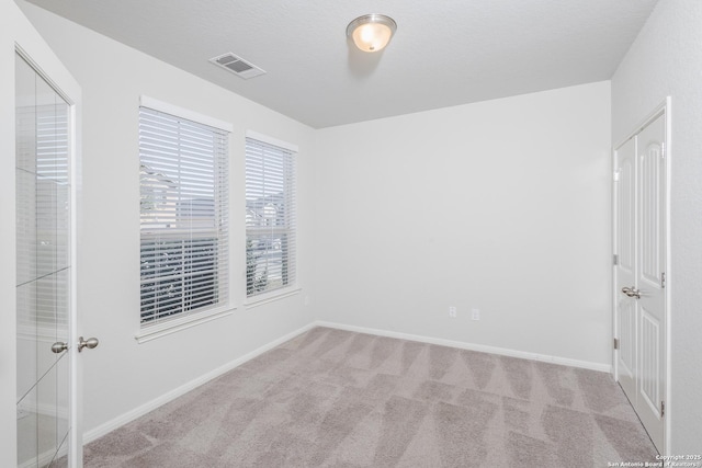 carpeted empty room with a textured ceiling